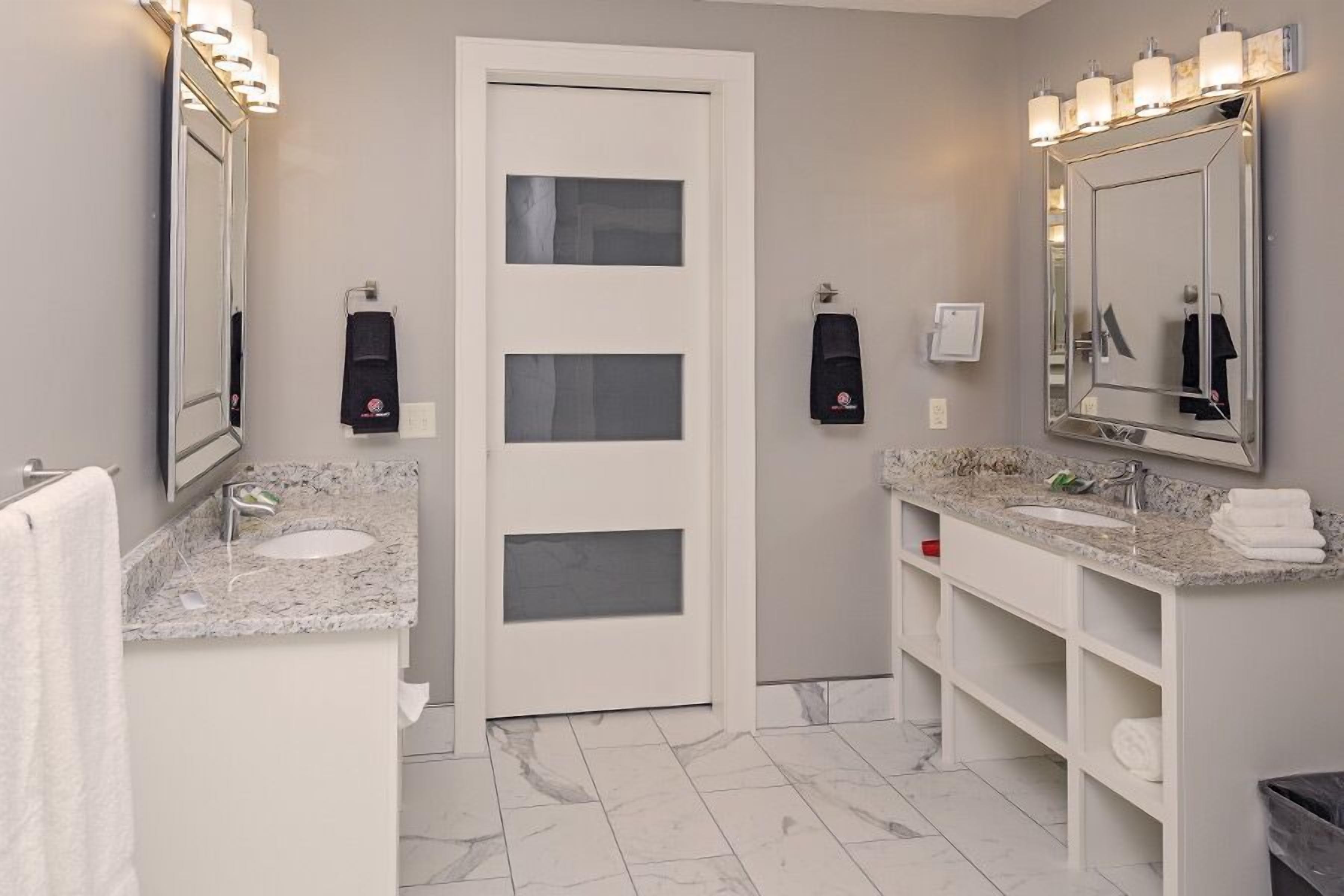A modern bathroom with two sinks, a large mirror, and built-in shelves.