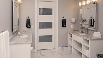 A modern bathroom with two sinks, a large mirror, and built-in shelves.