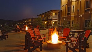An outdoor seating area with Adirondack chairs and a central fire pit. - Berlin Resort (Millersburg)