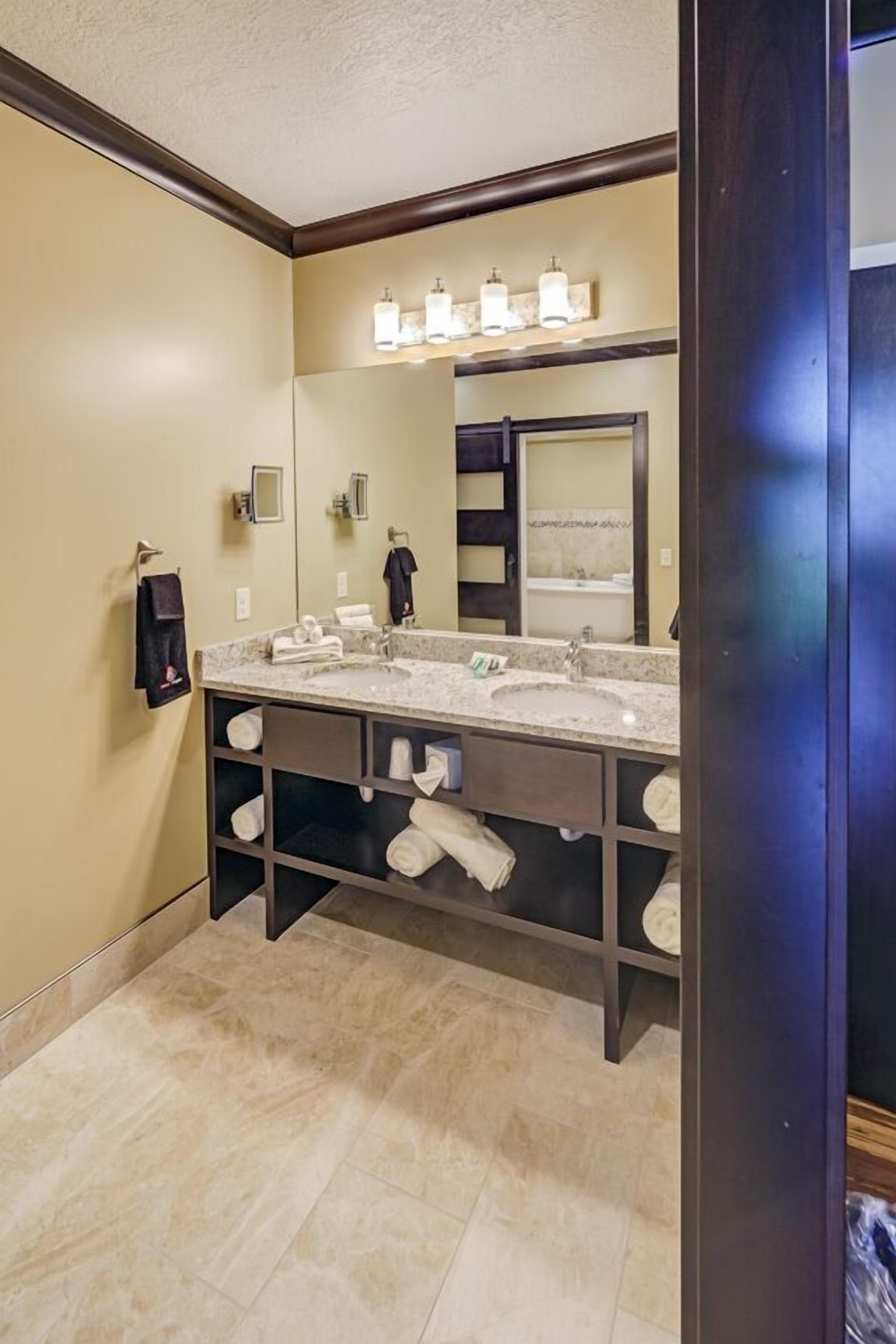 A bathroom with a double sink, a large mirror, and a towel rack.