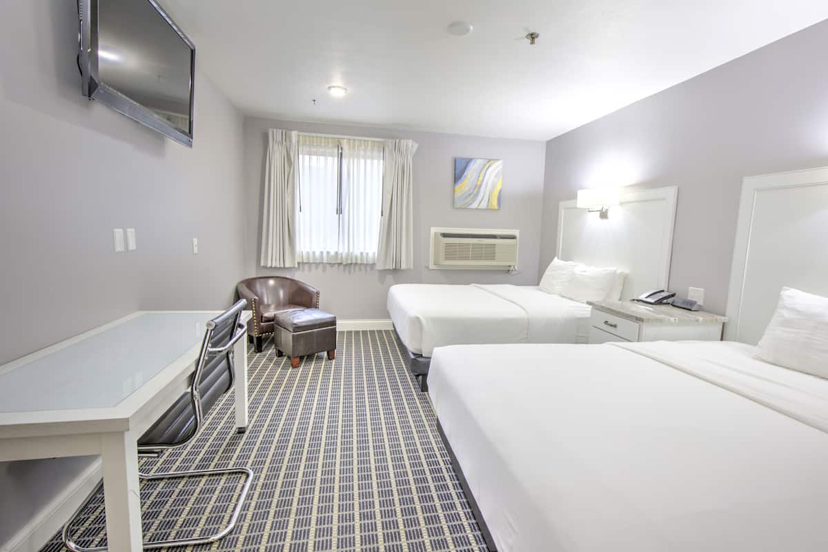 A hotel room with a bed, a desk, a chair, and a TV mounted on the wall.