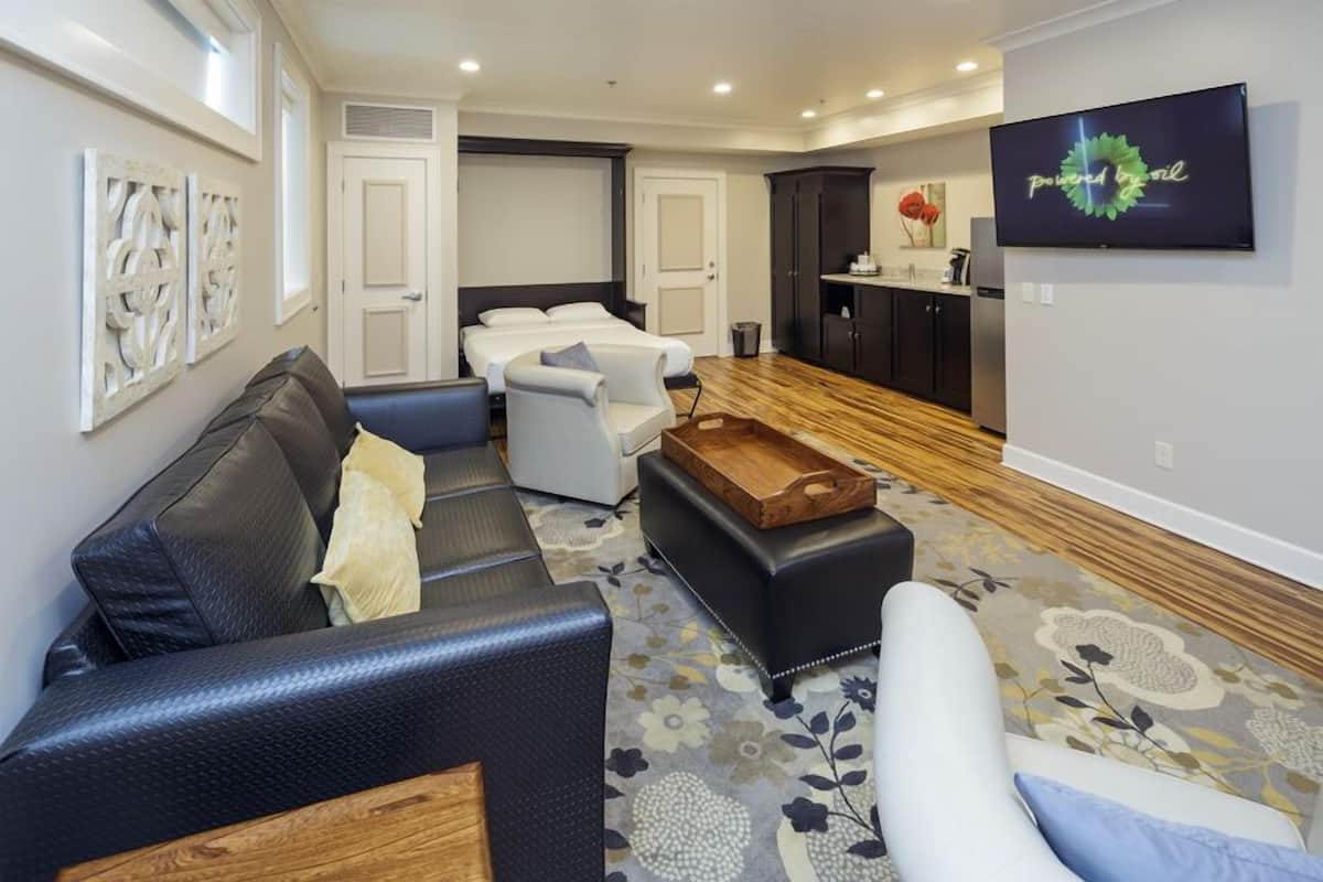 A modern living room with a sofa, armchairs, a coffee table, and a TV mounted on the wall.
