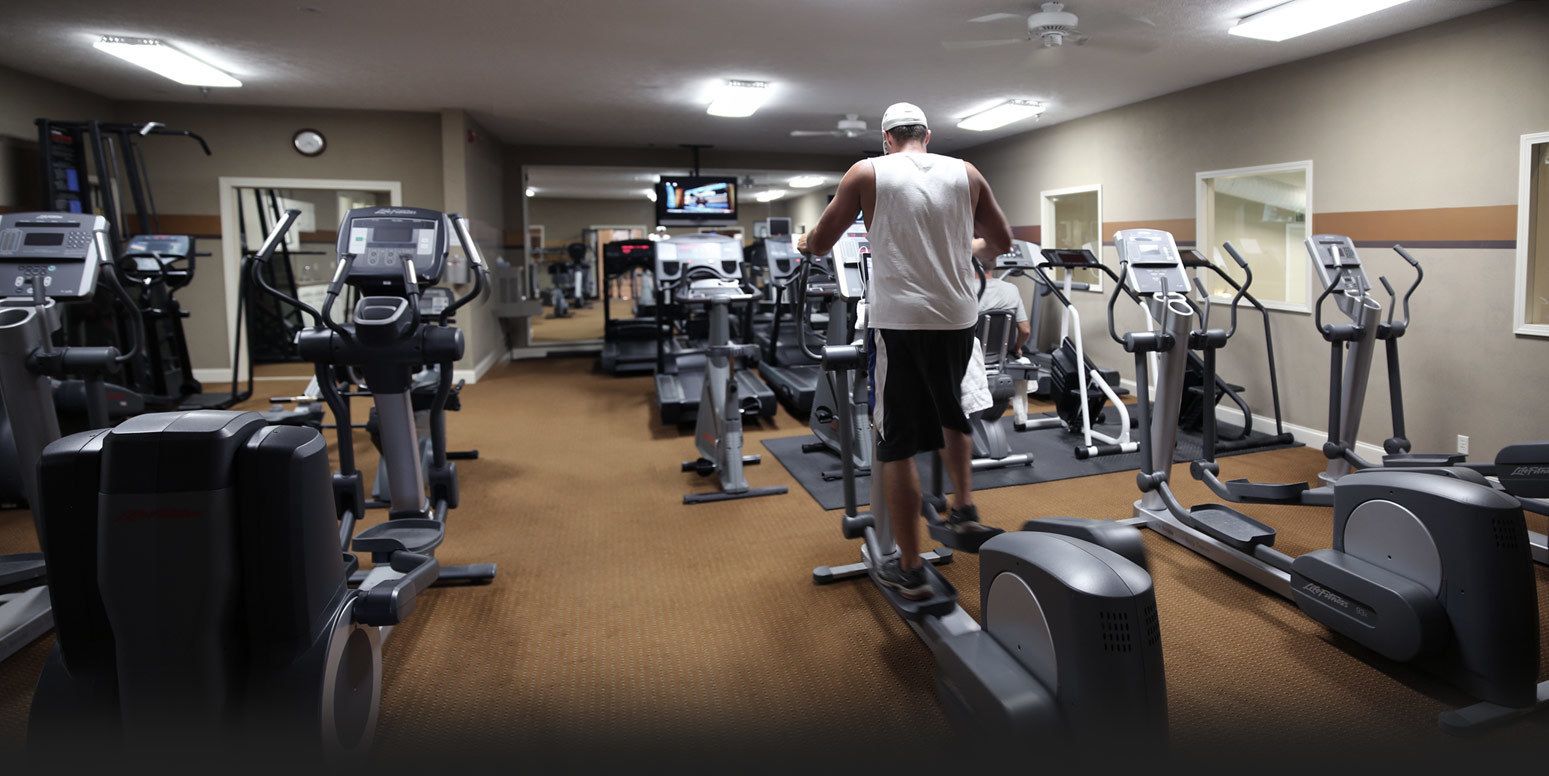Un gimnasio con cintas de correr, elípticas y equipo de pesas.