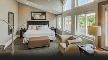 A hotel room with a large bed, a desk with a lamp, a chair, and a view of the outdoors.