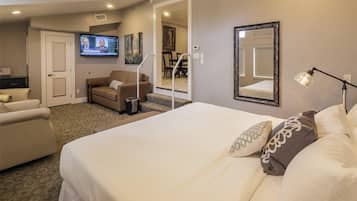 A hotel room with a bed, a sofa, a TV, a mirror, and a lamp.