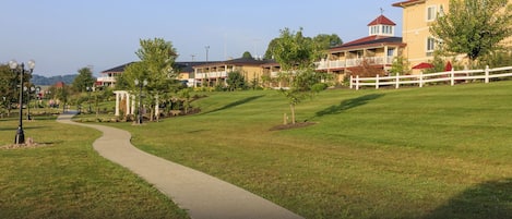 A pathway leading to a row of residential-style buildings with balconies and a white fence.