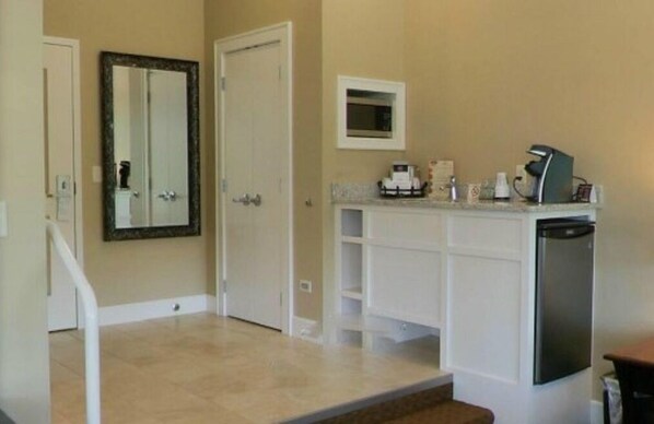 Une salle de bain avec un meuble-lavabo blanc, un miroir, un four à micro-ondes et une machine à café.