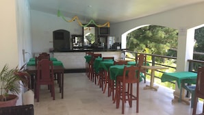 A restaurant with outdoor seating, a kitchen area, and a view of greenery. - Sosua Sunset Hotel (Sosúa)