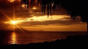 A sunset over a body of water with a silhouette of a mountain range in the distance. - Sosua Sunset Hotel (Sosúa)