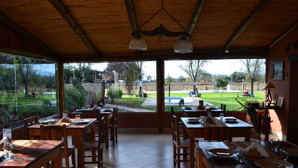 Un restaurante con mesas y sillas de madera, amplias ventanas que ofrecen vistas al exterior.