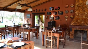 Un comedor rústico con mesas y sillas de madera, una chimenea de piedra y varios platos decorativos en la pared.
