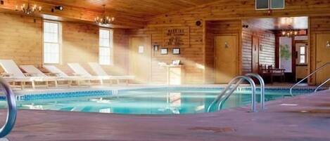 A wooden cabin with a swimming pool, lounge chairs, and a staircase leading to a door.