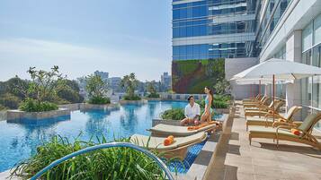 Una piscina al aire libre, sombrillas, sillones reclinables de piscina