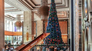 Een vleugelpiano in een ruime lobby, met een grote kerstboom en elegante kroonluchters.