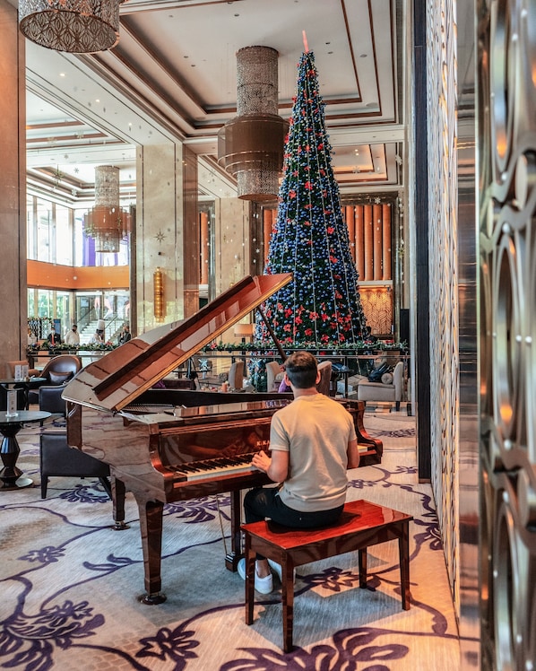 A grand piano in a spacious lobby with a large Christmas tree and elegant chandeliers. - Shangri-La Bengaluru (Bengaluru)