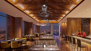 Een modern restaurant met hoge plafonds, houten lambrisering en uitzicht over de stad.