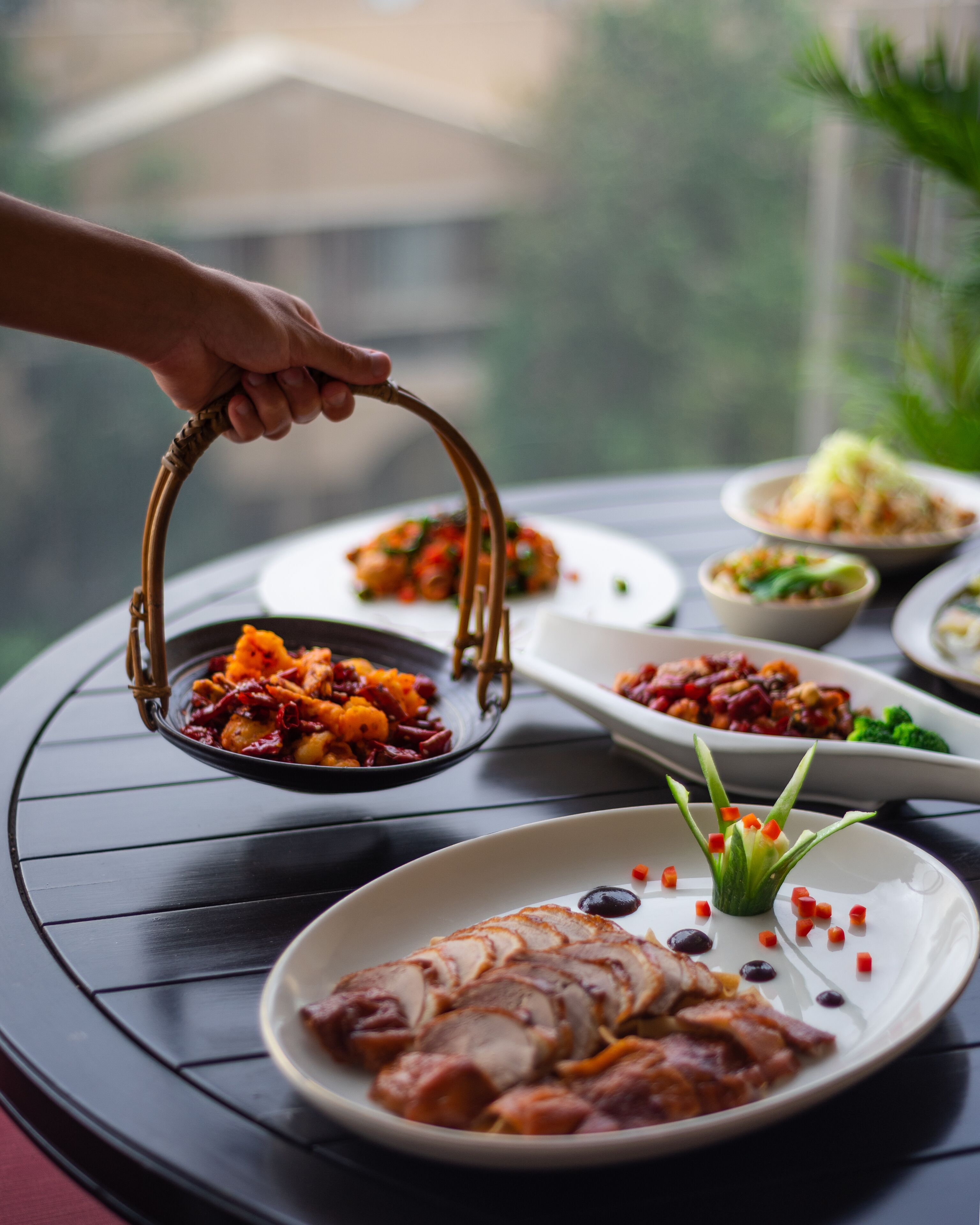 Una mesa con diversos platos, incluyendo un recipiente con comida que se levanta con palillos.
