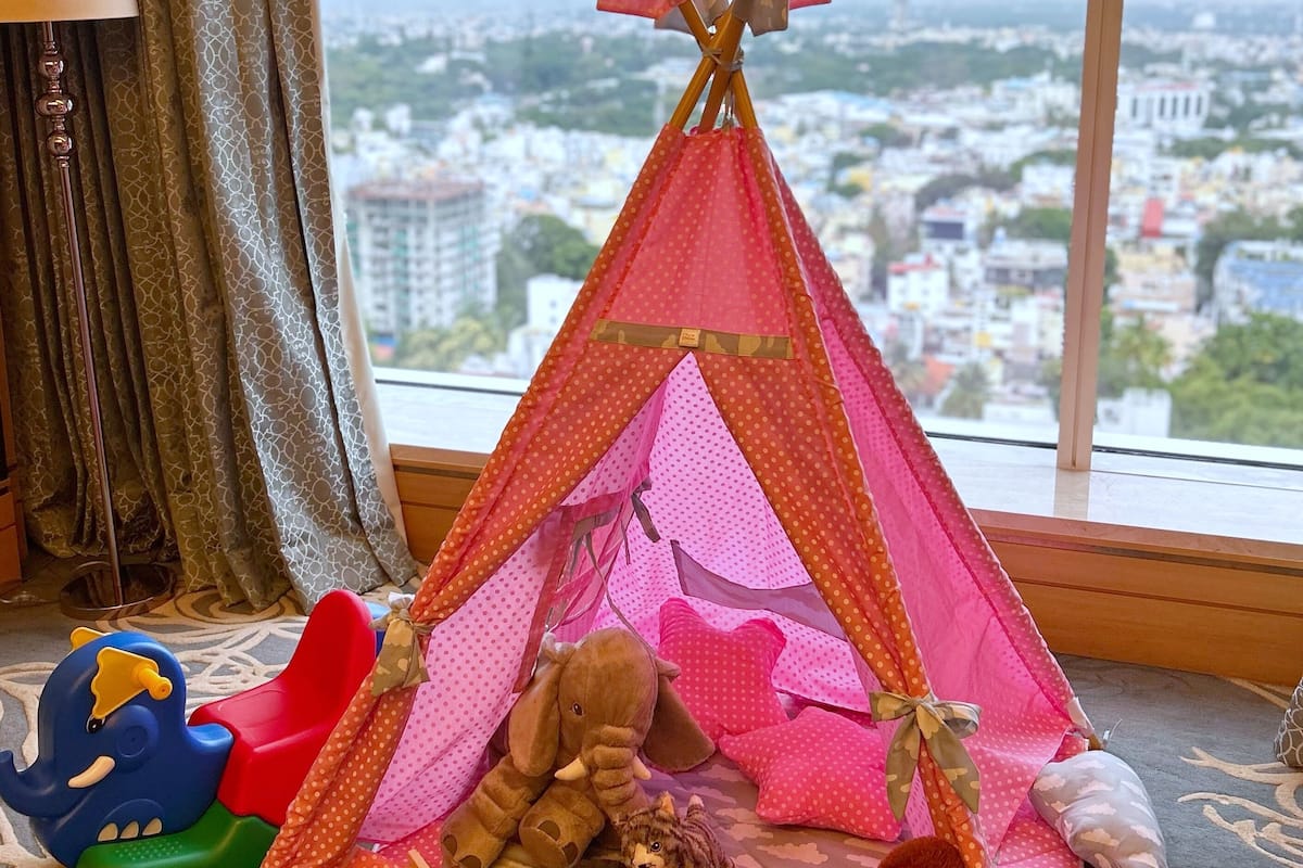 A room with a large window, a pink tent, and various toys on the floor.