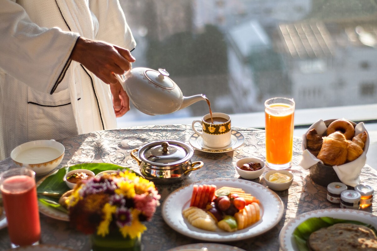 A breakfast table with various dishes, a teapot, and a glass of orange juice.