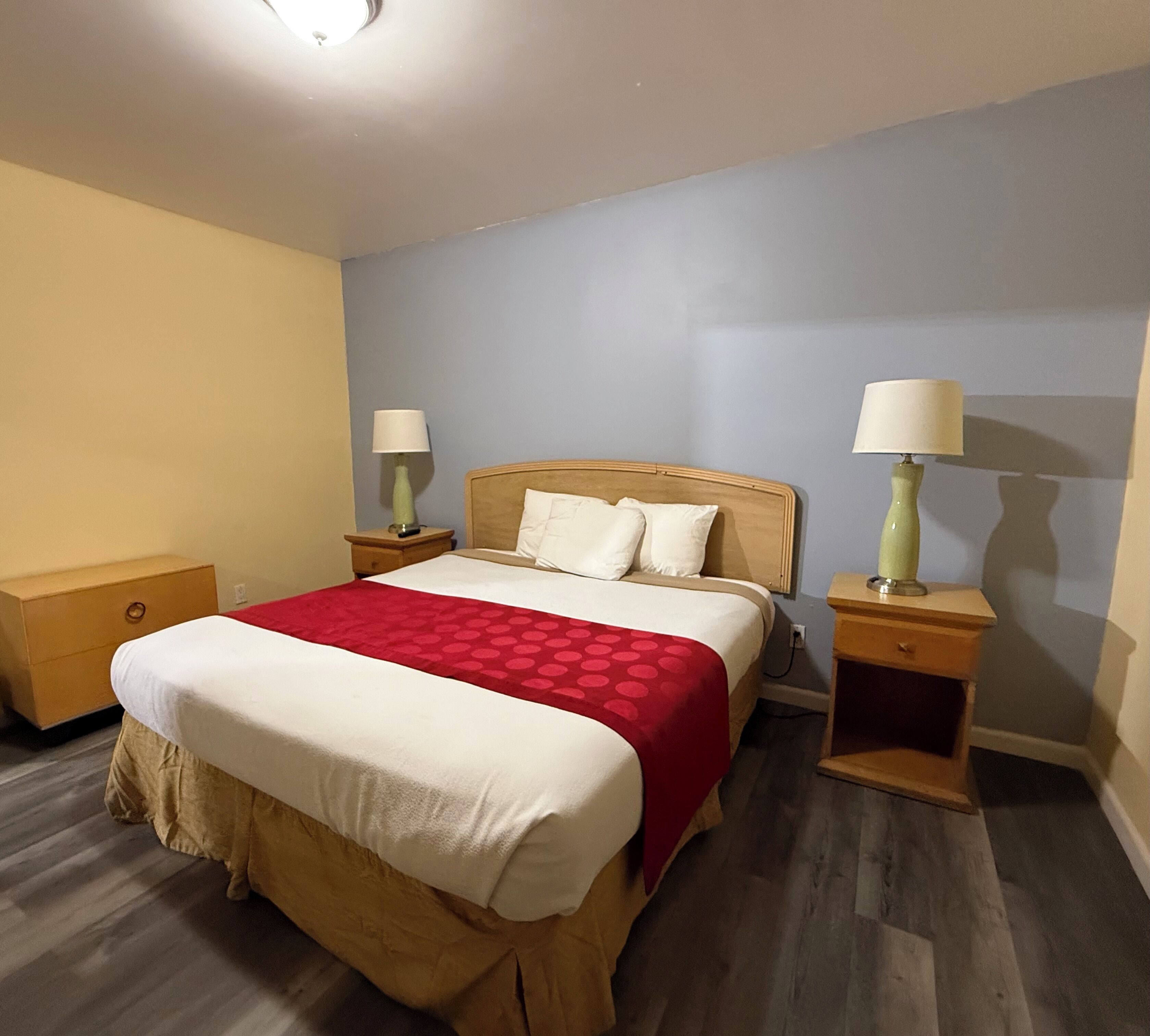 A hotel room with a bed, two bedside tables, and a nightstand.
