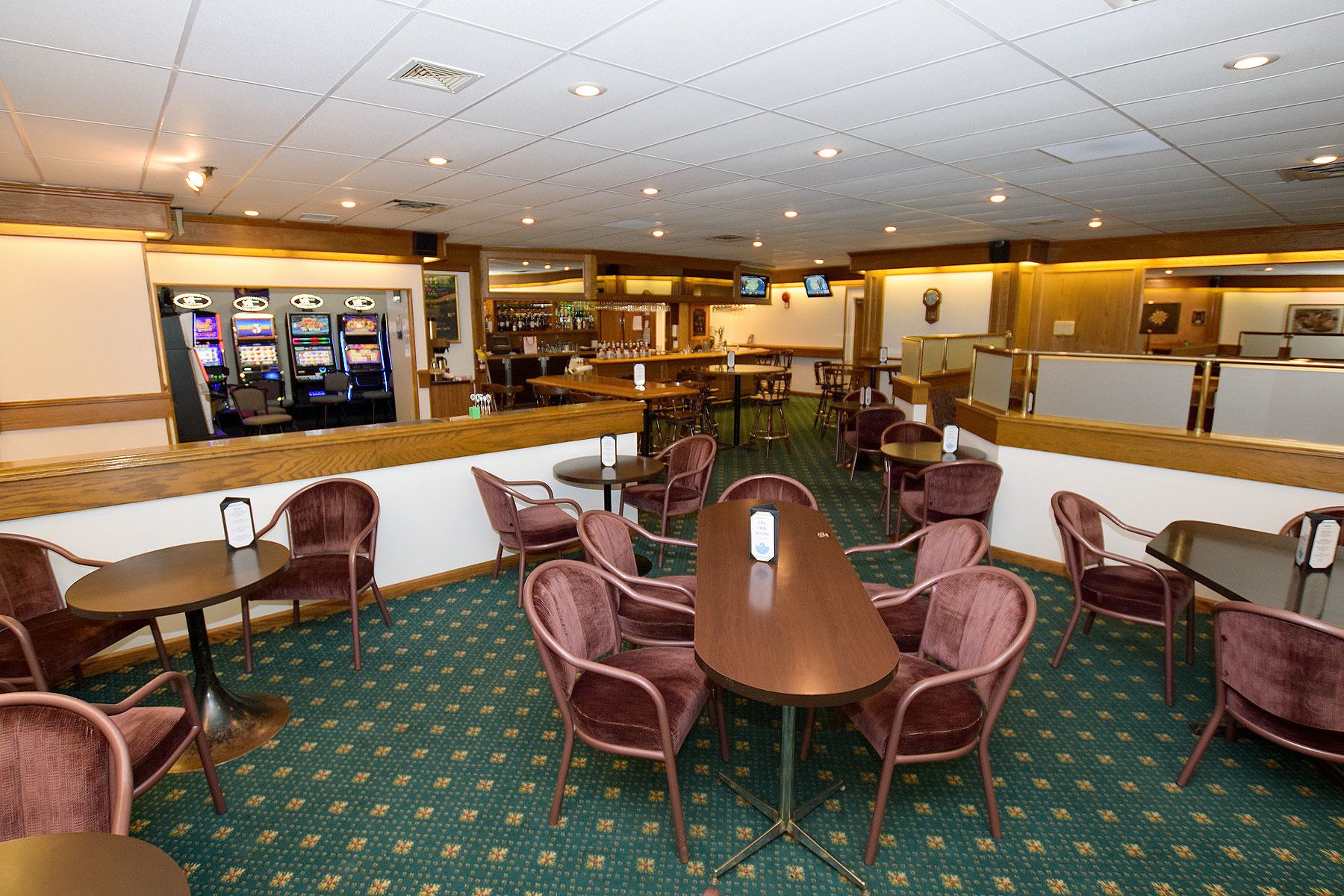 A hotel lobby with a bar area, gaming machines, and several seating arrangements.