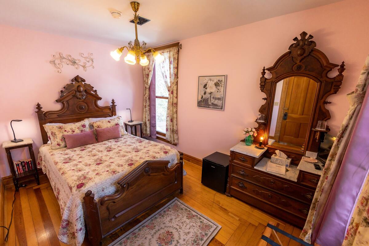 Une chambre à coucher avec un lit en bois, une commode, un miroir et une table de chevet.