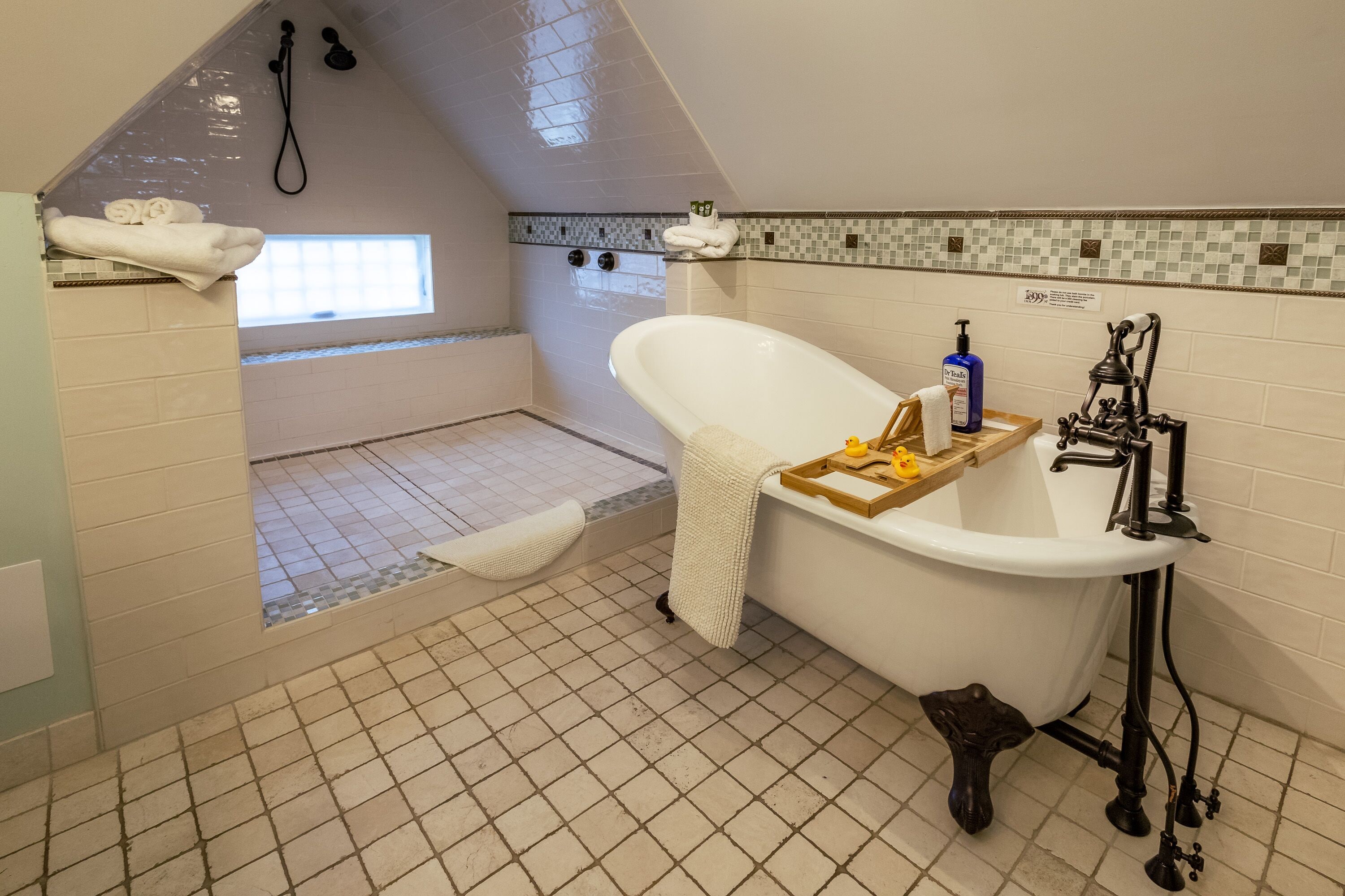 A bathroom with a freestanding bathtub, a shower, and a window providing natural light.