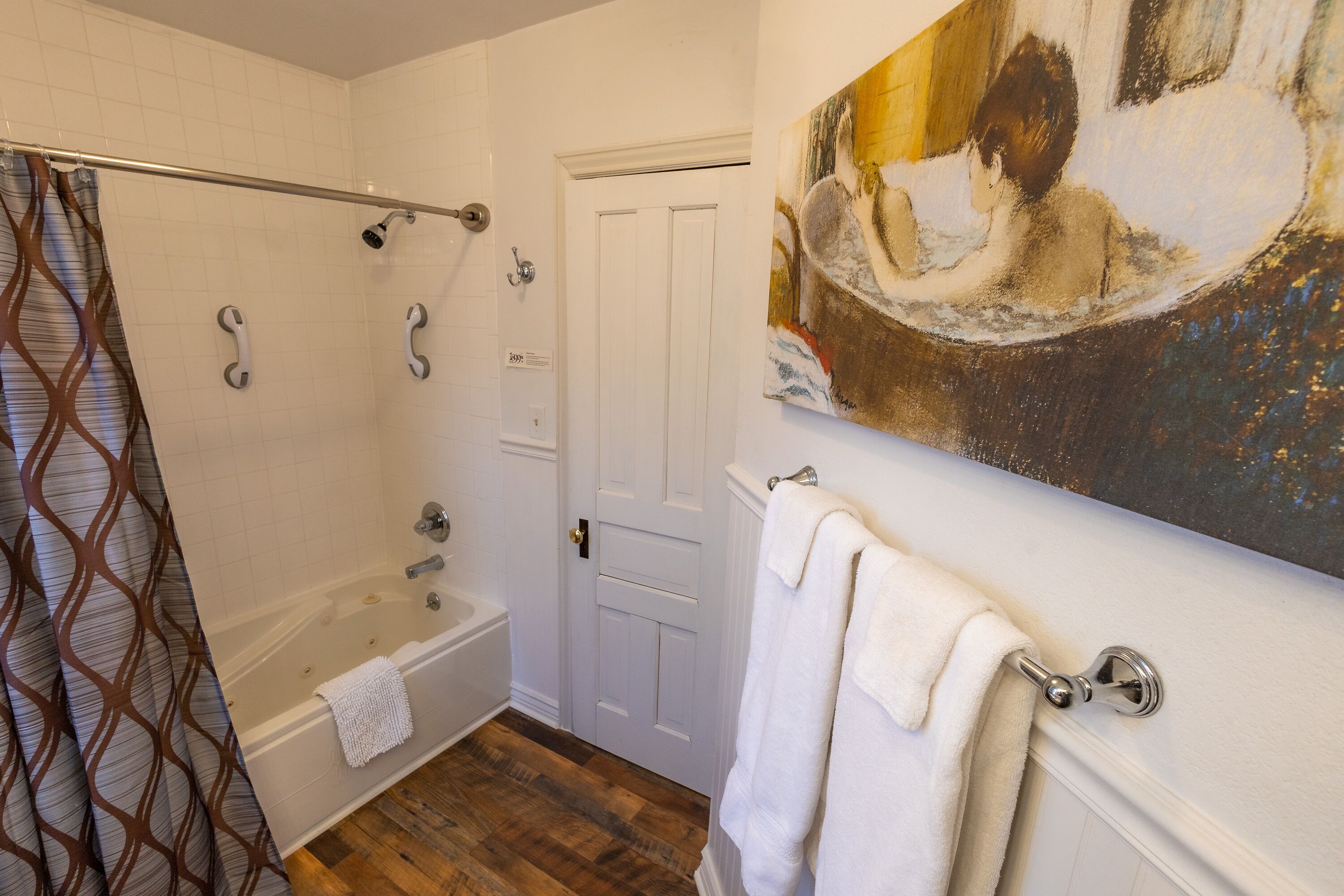 A bathroom with a shower, bathtub, and a painting on the wall.