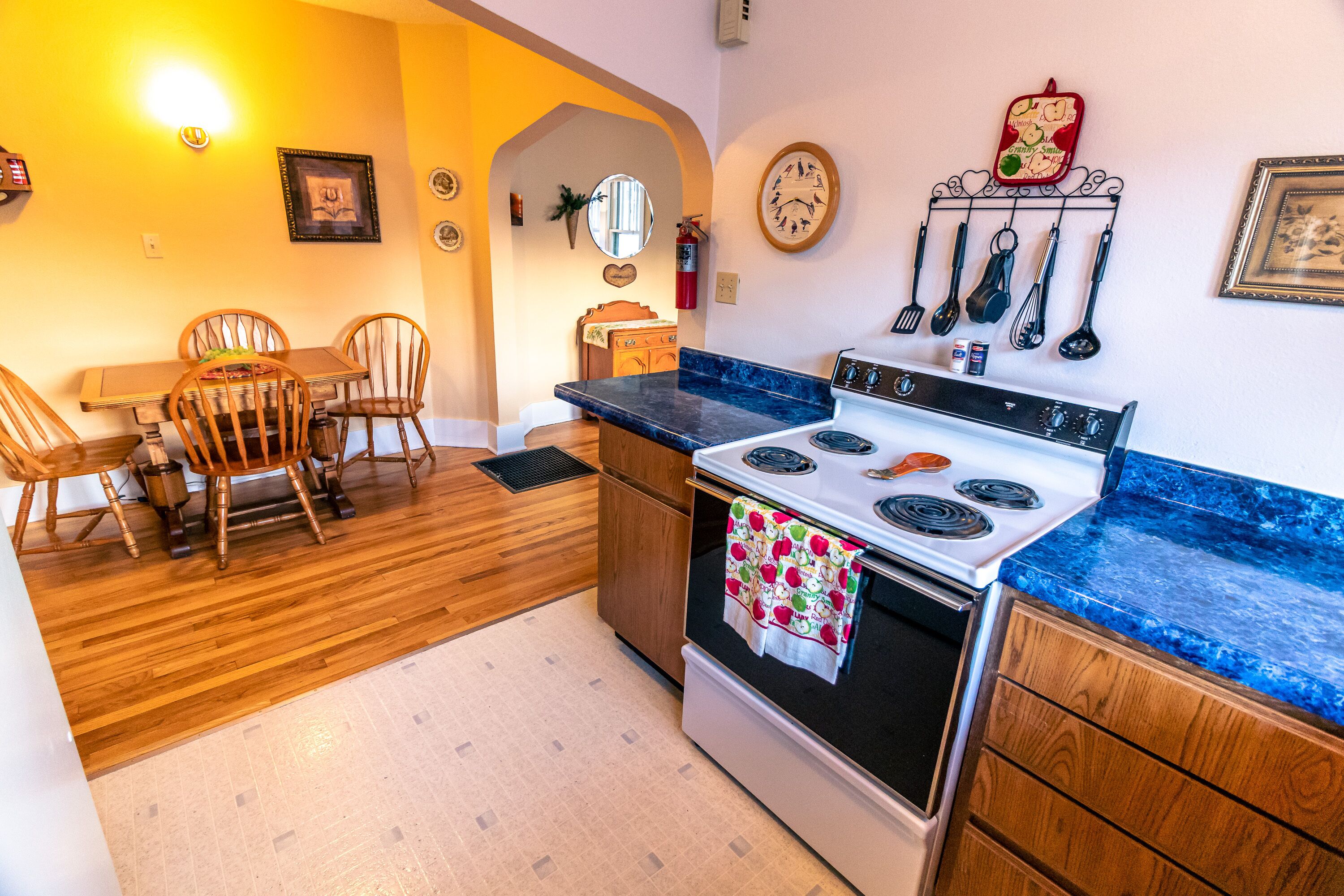 Une cuisine avec des meubles de rangement en bois, une cuisinière et un coin repas avec des chaises.