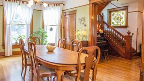 Een eetkamer met een houten tafel en stoelen, een kroonluchter en een piano.