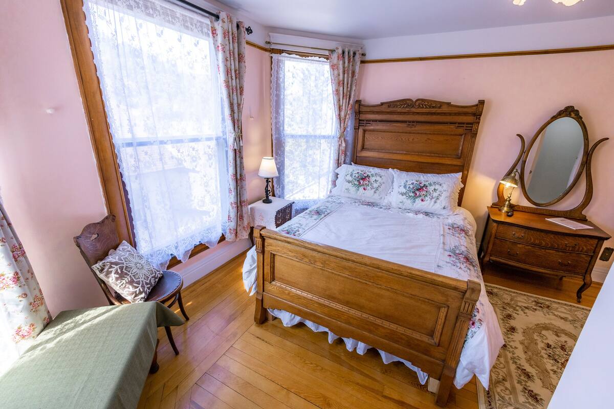 Une chambre à coucher avec un lit en bois, une table de chevet, une chaise et une commode.