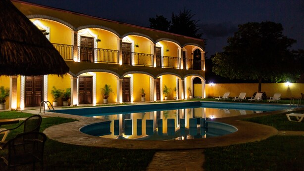 Un hotel con piscina, varios balcones y mobiliario exterior.