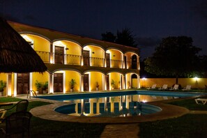 A hotel with a swimming pool, multiple balconies, and outdoor seating.