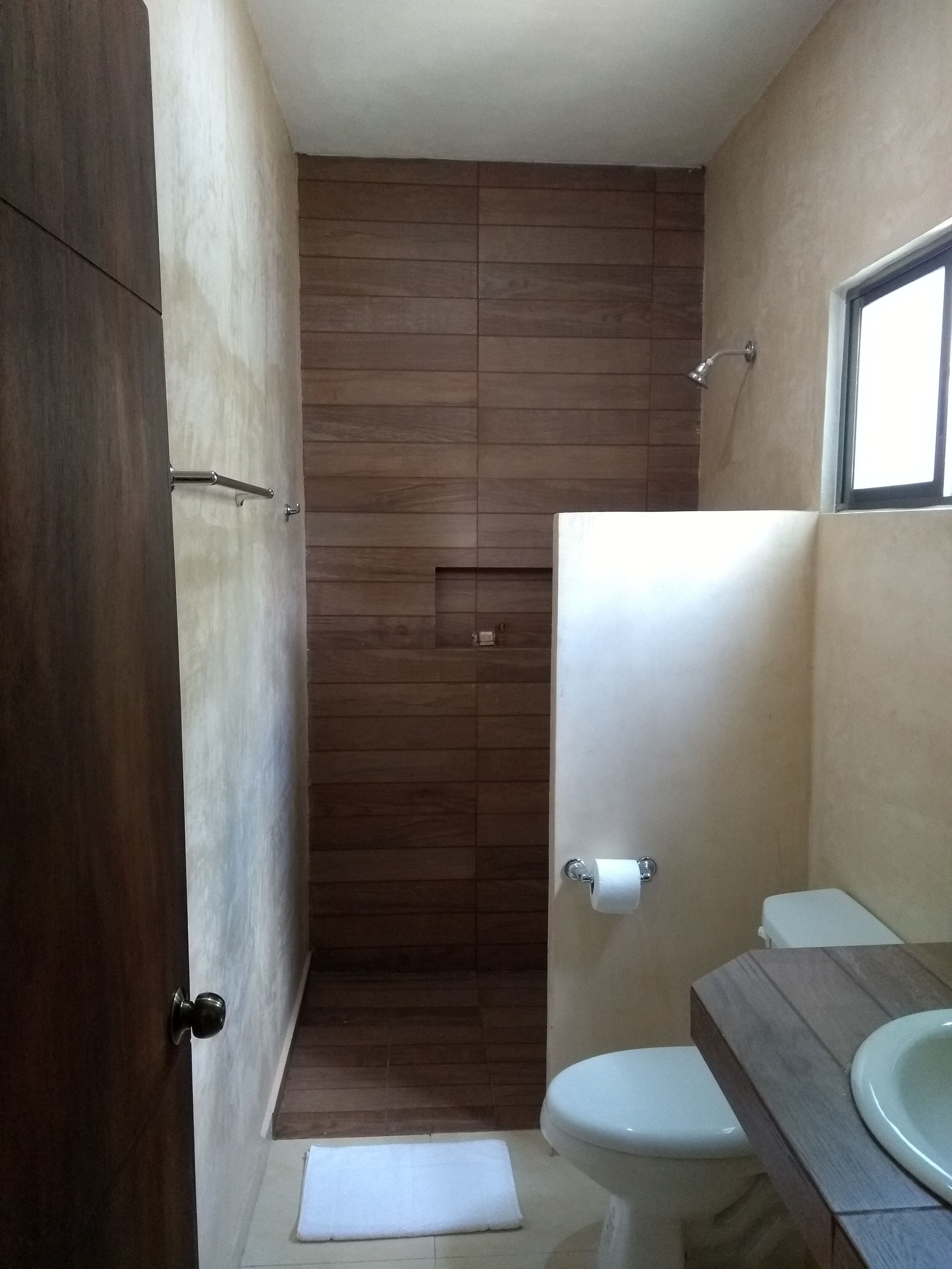 A bathroom with a wooden floor, a toilet, a sink, and a shower.