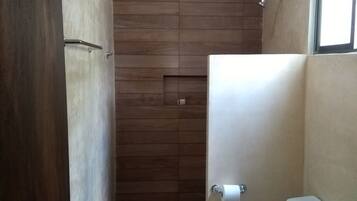 A bathroom with a wooden floor, a toilet, a sink, and a shower.