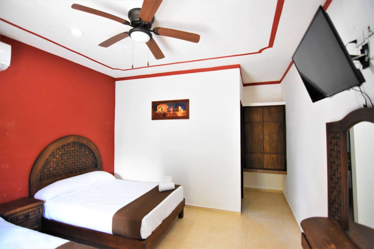 A bedroom with a bed, a ceiling fan, a TV, and a wooden wardrobe.