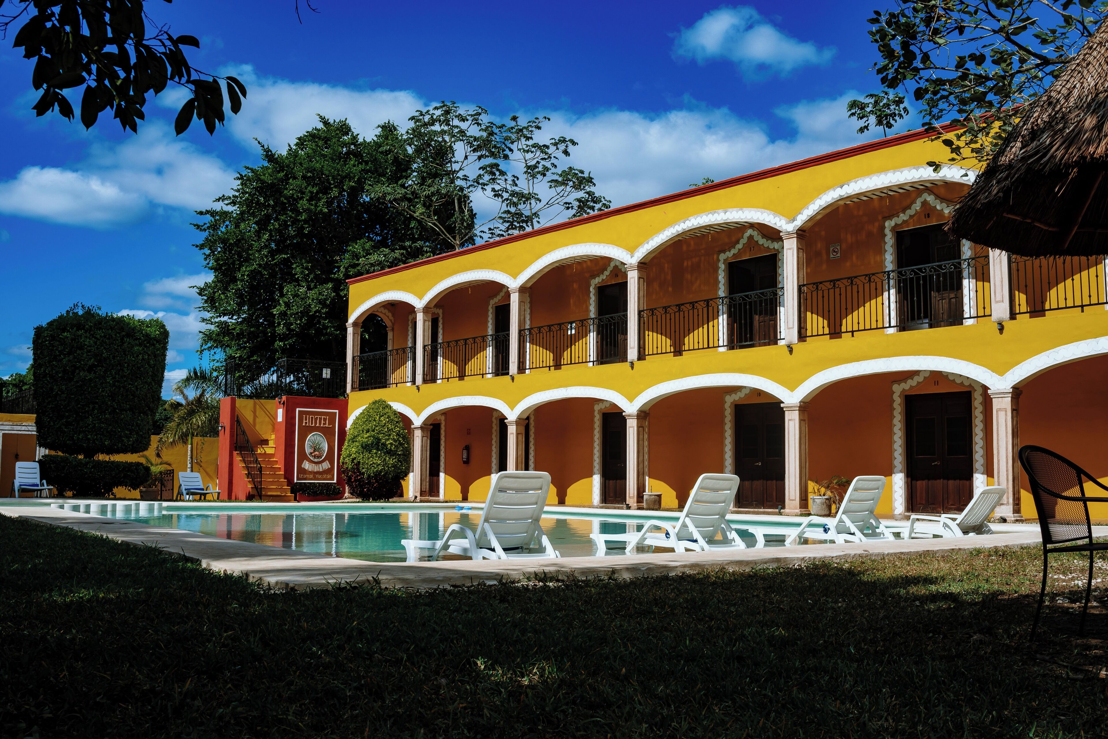 A hotel with a pool area, multiple balconies, and a tropical setting.