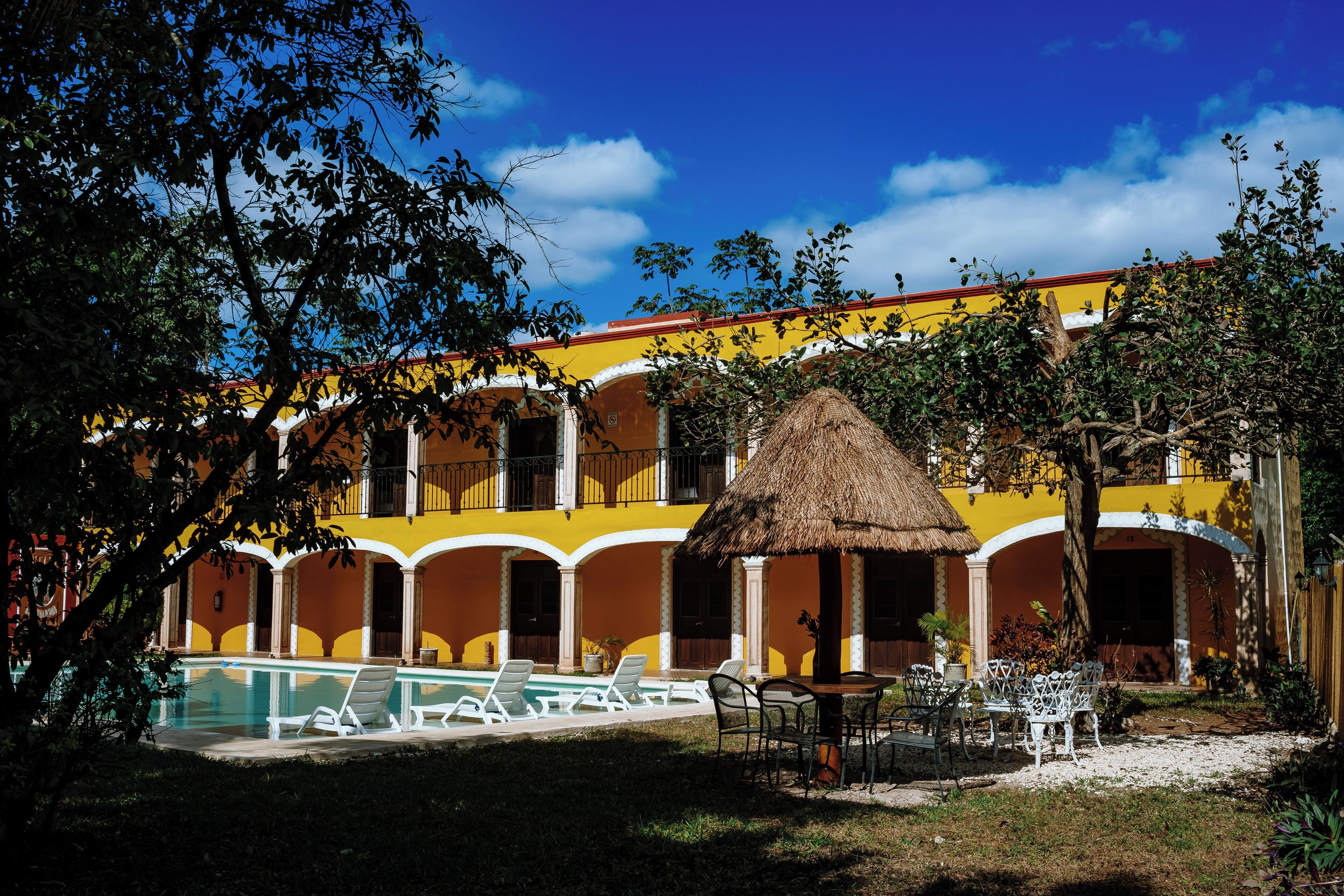 Un hôtel doté d’une piscine, d’un espace extérieur aménagé et d’une structure dont le toit est fait de chaume.