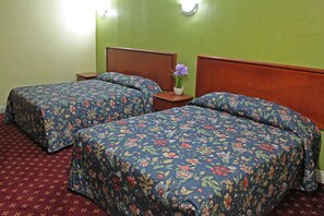 Una habitación con dos camas individuales, cada una con una colcha estampada, una mesita de noche y una pequeña mesa con un jarrón de flores.