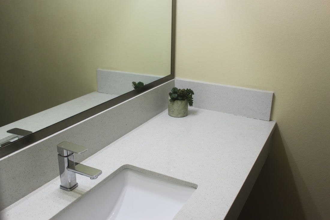A bathroom with a white sink, a mirror, and a small potted plant.