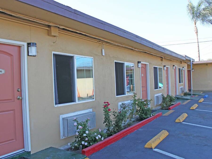 A motel with a row of rooms, each with a window and a door.