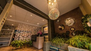 A hotel reception area with a modern design, including a reception desk, decorative wall panels, and a variety of plants. - Los Leones Hotel Boutique (Arequipa)