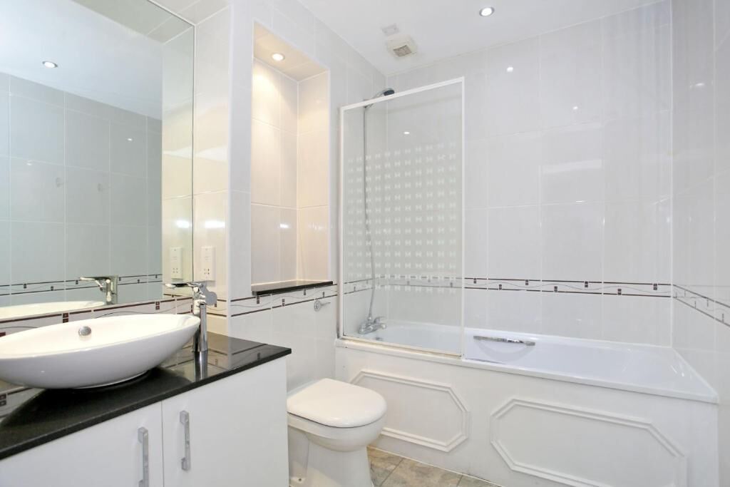 Een moderne badkamer met een wit wastafelmeubel, toilet en bad.