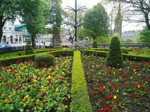 A formal garden with neatly trimmed hedges, a central statue, and a variety of flowers. - Aspect Apartments City Centre (Aberdeen)