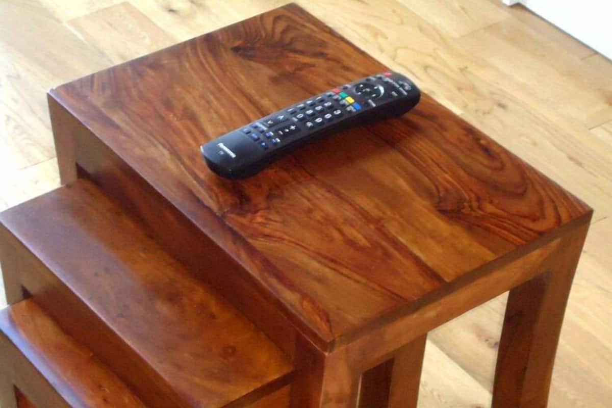 A wooden table with a remote control on top.