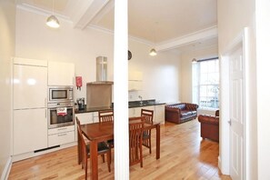A modern kitchen with built-in appliances and a dining area with wooden furniture. - Aspect Apartments City Centre (Aberdeen)