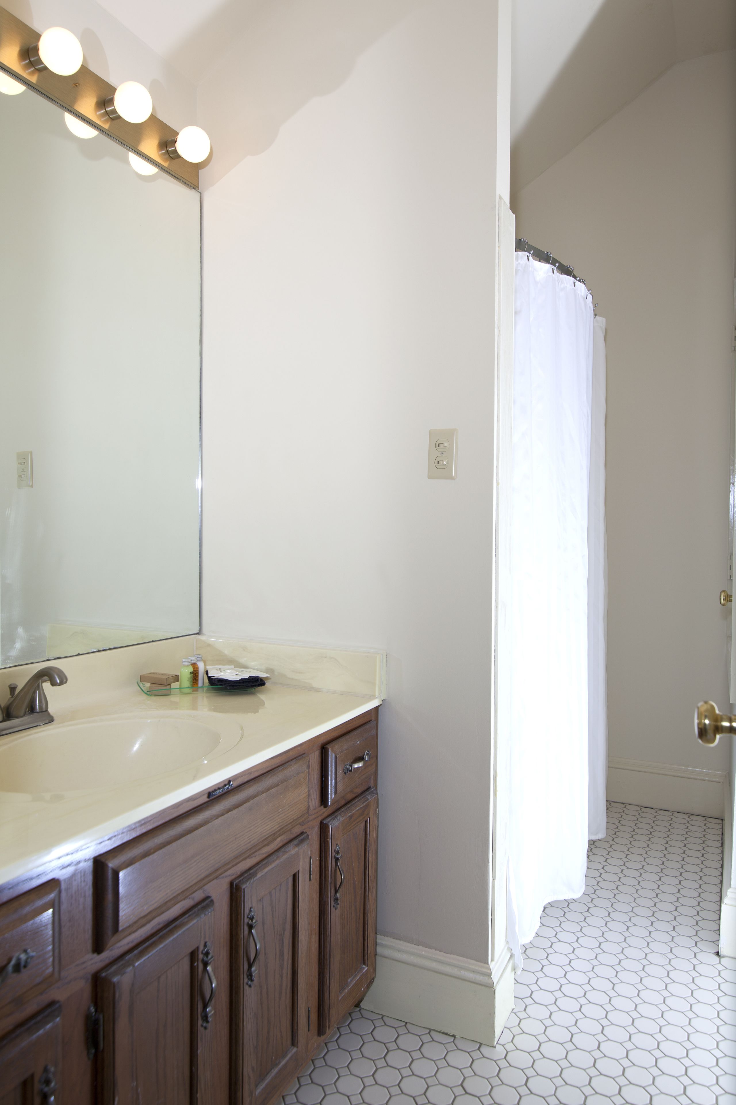 A bathroom with a double sink, vanity, and a shower curtain.