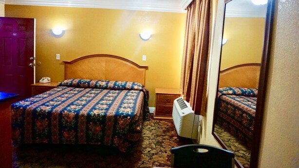 A hotel room with two beds, a large mirror, a standing heater, and a door with a number sign. - Satellite Motel (Los Angeles)