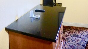 A room with a flat-screen TV mounted on the wall, a small table with a remote and a glass, and a framed picture on the wall. - Satellite Motel (Los Angeles)