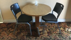 A small round wooden table with two black chairs. - Satellite Motel (Los Angeles)